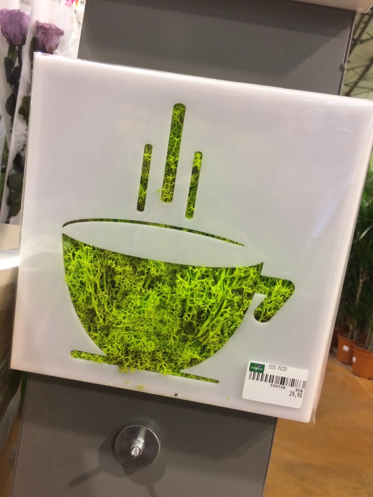 Tableau en plastique blanc avec forme de tassede thé sur fond végétal vert mousse