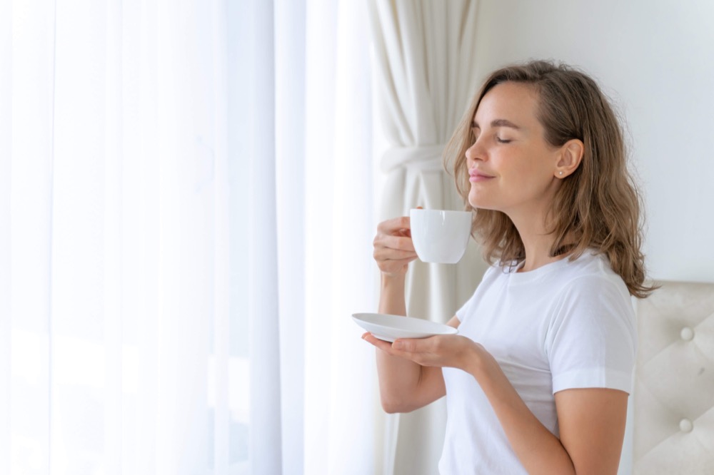 femme buvant du thé devant sa fenêtre