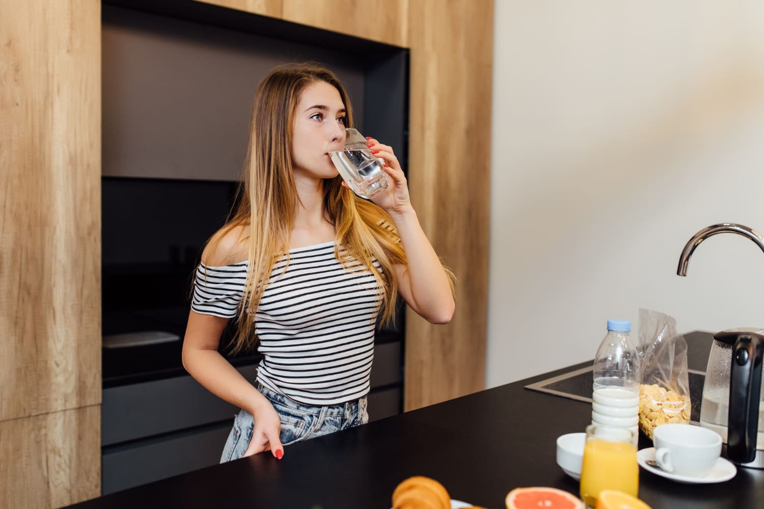 femme buvant de l'eau le matin dans sa cuisine