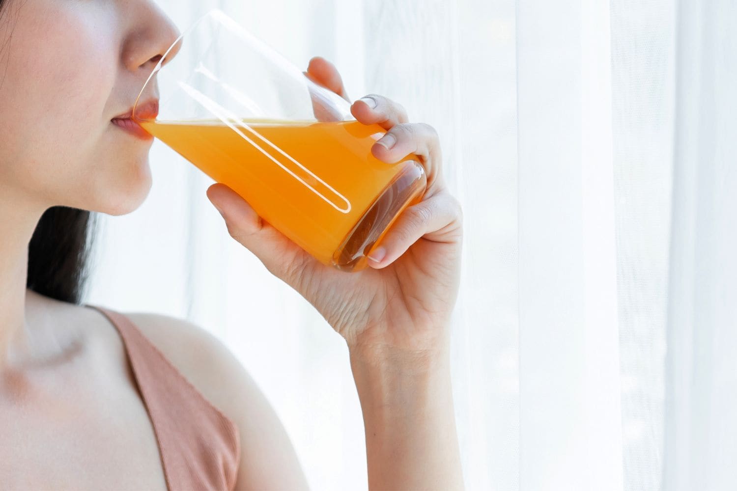 jeune femme boit un verre de jus d'orange