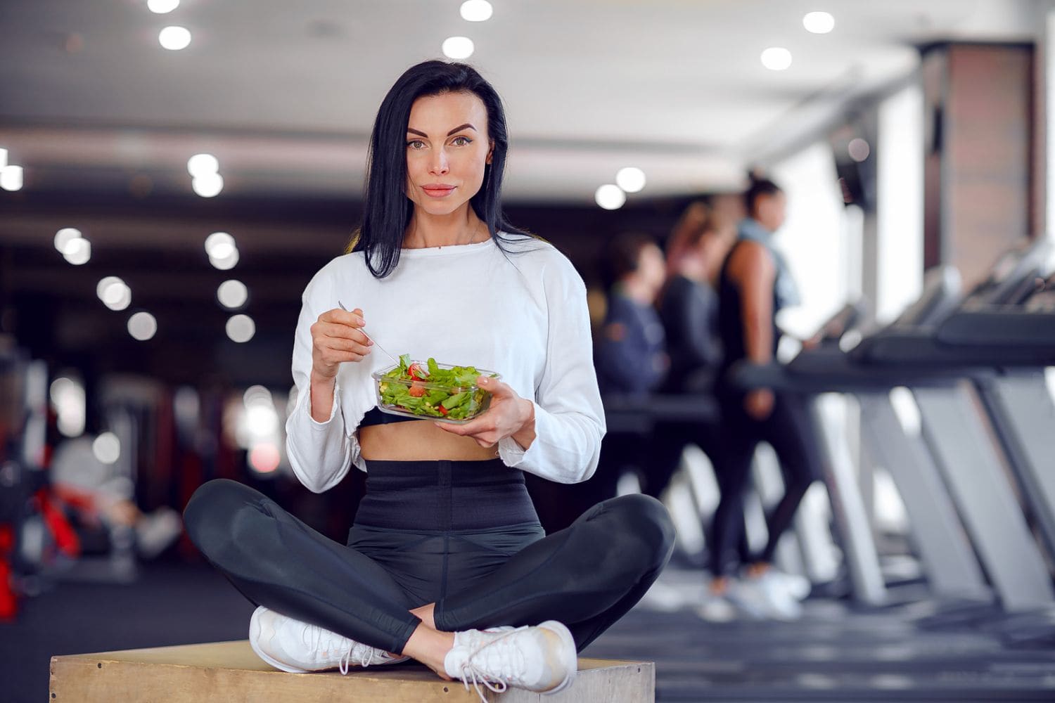 femme mange une salade dans une salle de sport