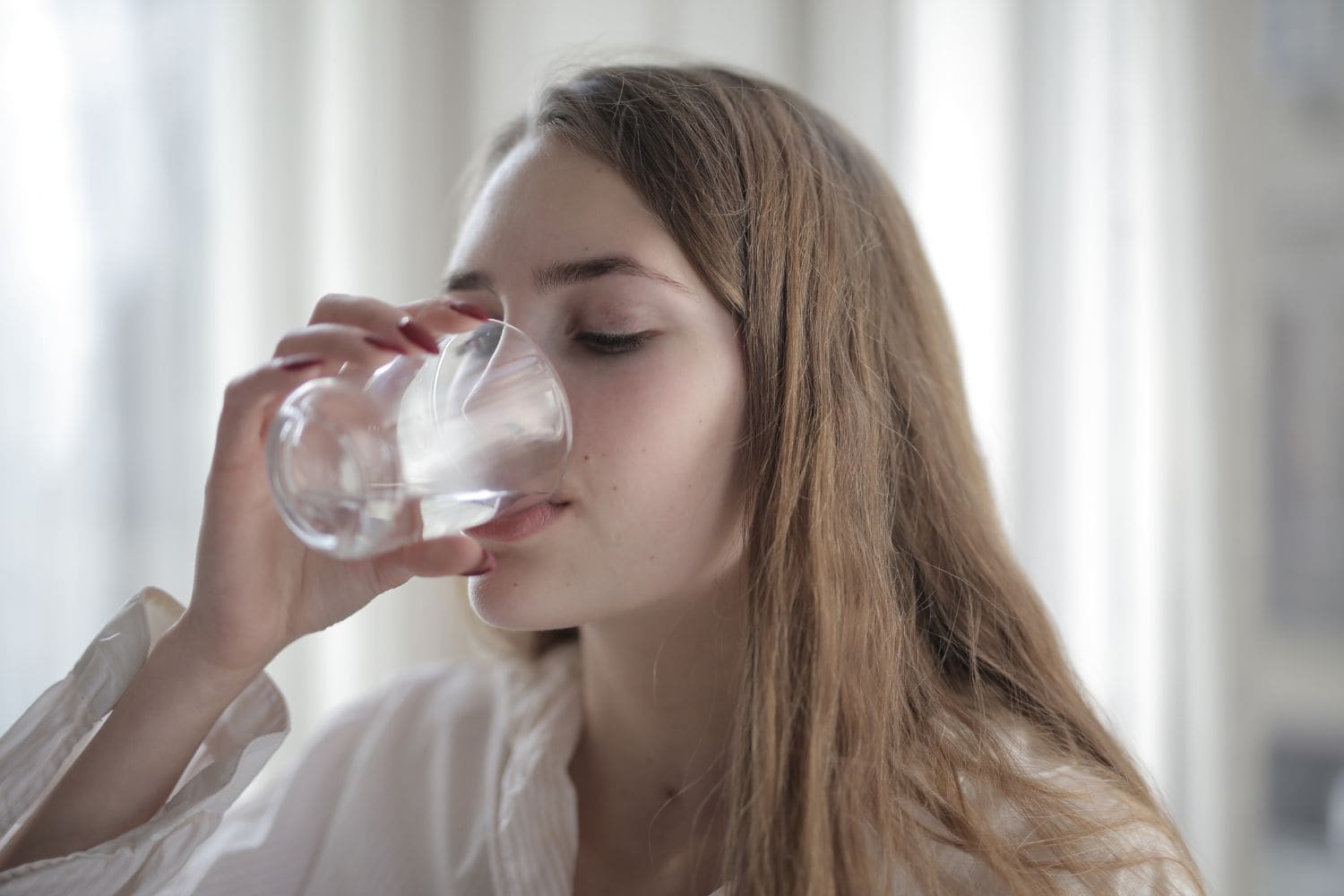 jeune femme boit de l'eau dans un verre