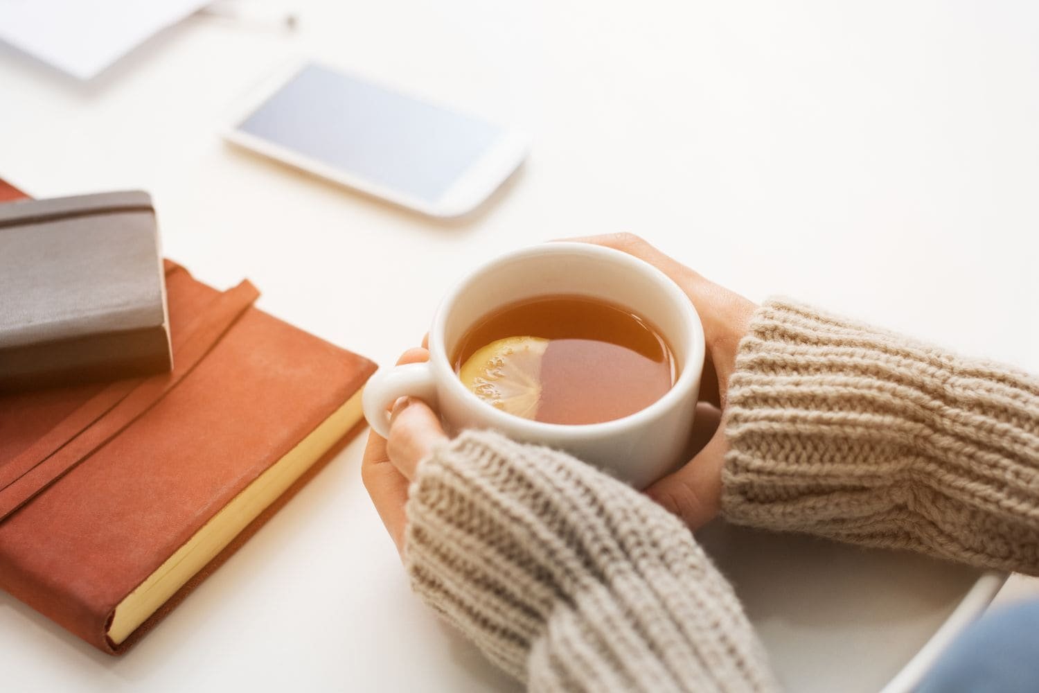mug de thé sur une table tenu entre deux main lors d'une pause au travail