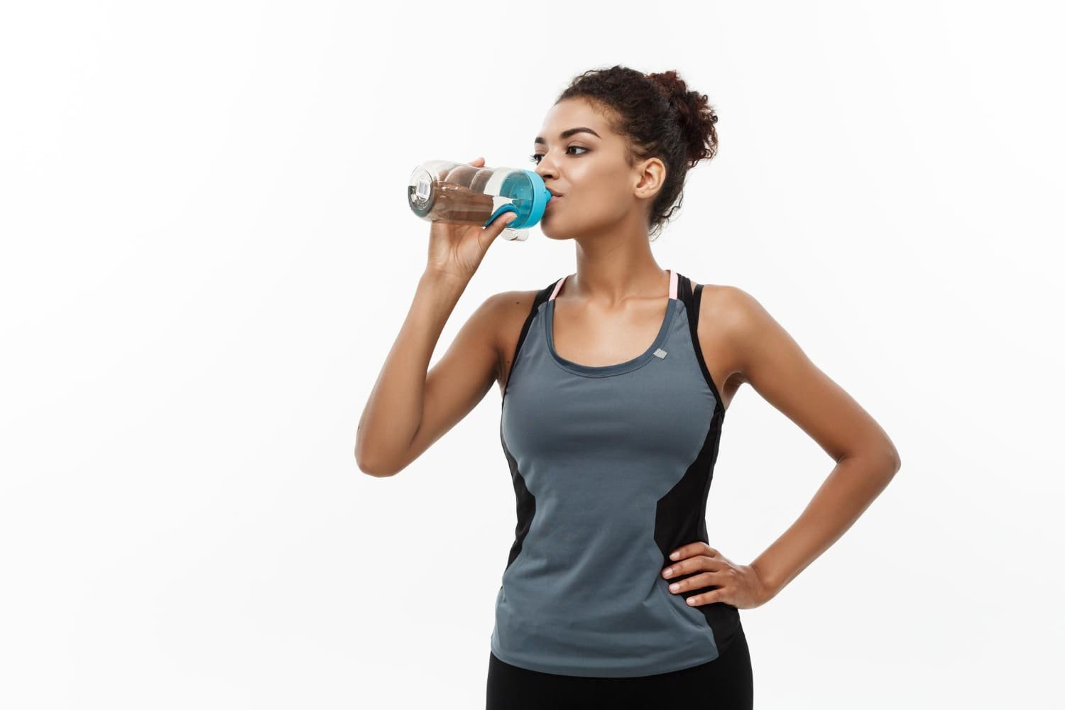 femme buvant de l'eau sur fond blanc en tenue de sport