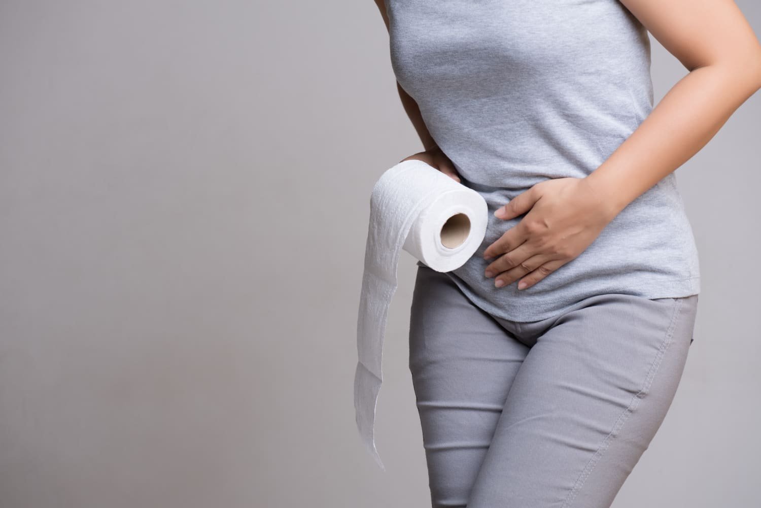femme tenant du papier toilette et se tenant le ventre
