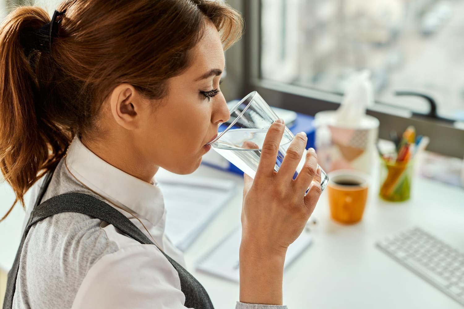 jeune femme boit dans un verre d'eau du robinet