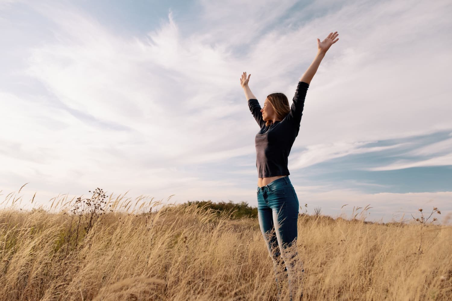 jeune femme heureuse dans un champ lève les bras